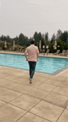 Man walking into the pool in a pink shirt.